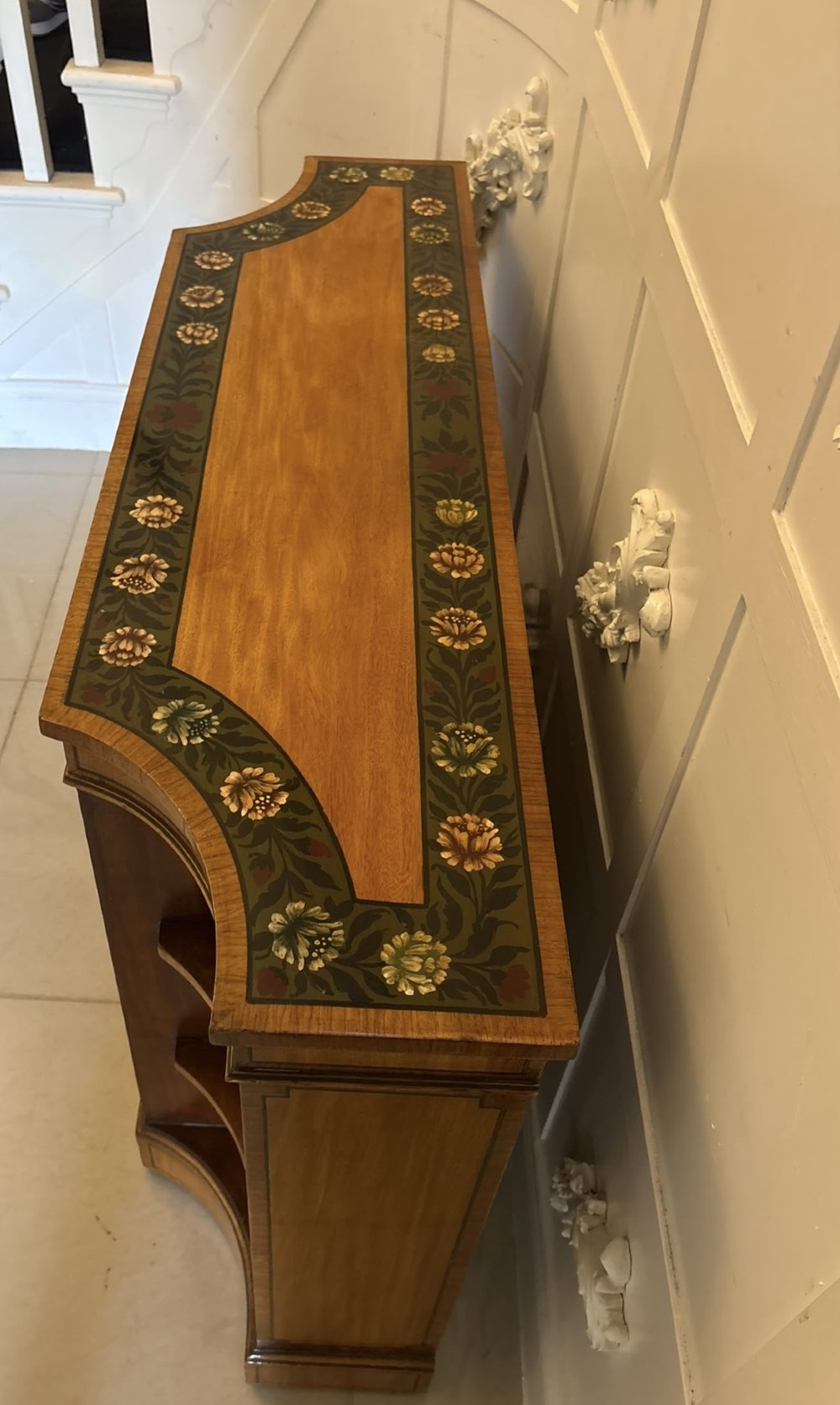 A Sheraton Revival satinwood side cabinet featuring painted leaf borders, central doors with fan-shaped woven cane panels, and open curved side shelves. View VI