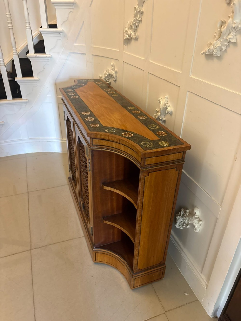 A Sheraton Revival satinwood side cabinet featuring painted leaf borders, central doors with fan-shaped woven cane panels, and open curved side shelves. View XIV