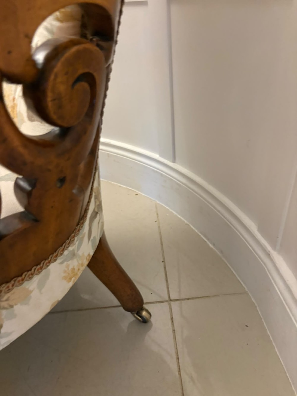 A Victorian walnut armchair featuring floral button-tufted upholstery, carved open scroll arms, and front legs set on brass castors. View VIII