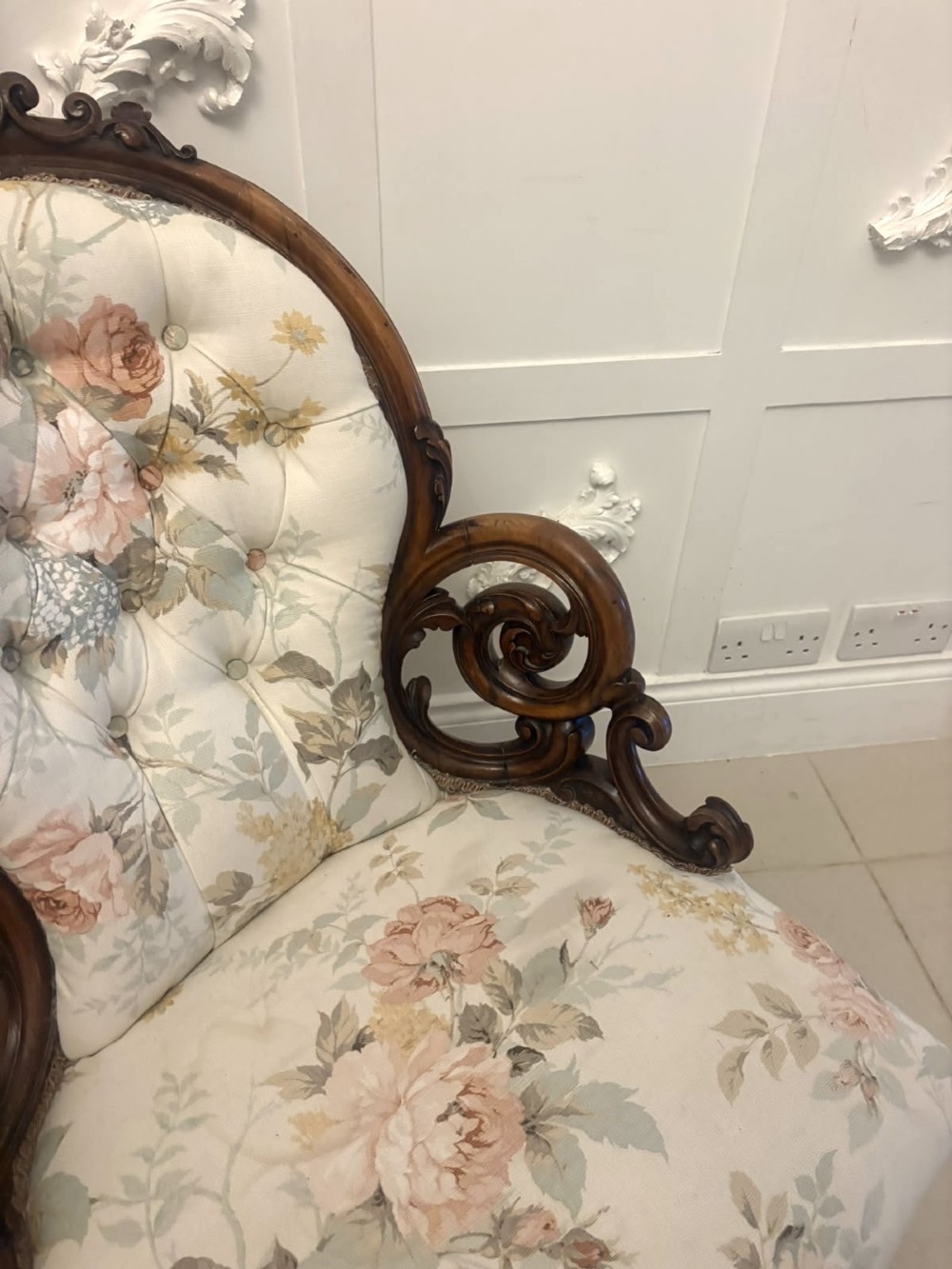 A Victorian walnut armchair featuring floral button-tufted upholstery, carved open scroll arms, and front legs set on brass castors. View XIII
