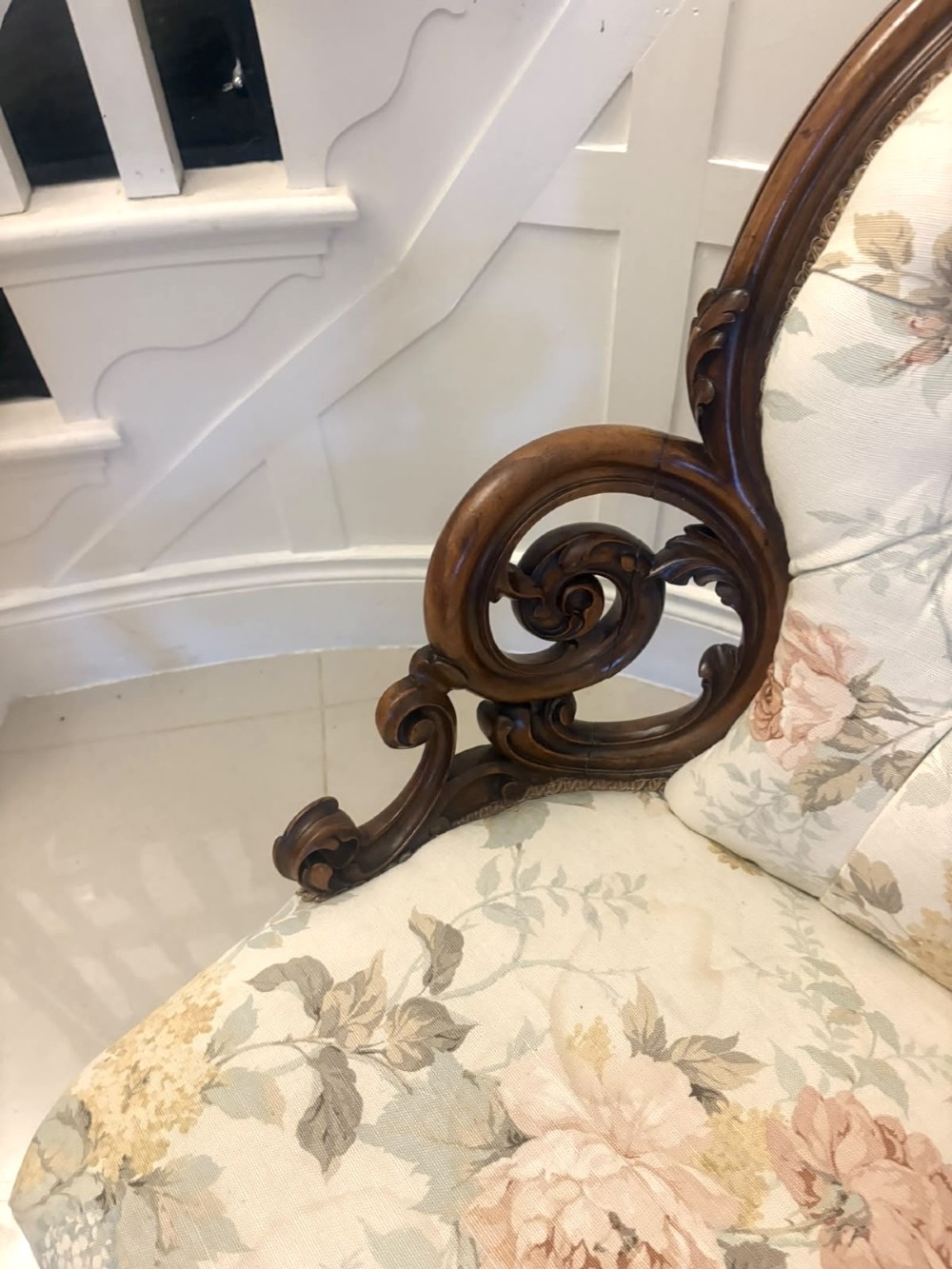 A Victorian walnut armchair featuring floral button-tufted upholstery, carved open scroll arms, and front legs set on brass castors. View XIV