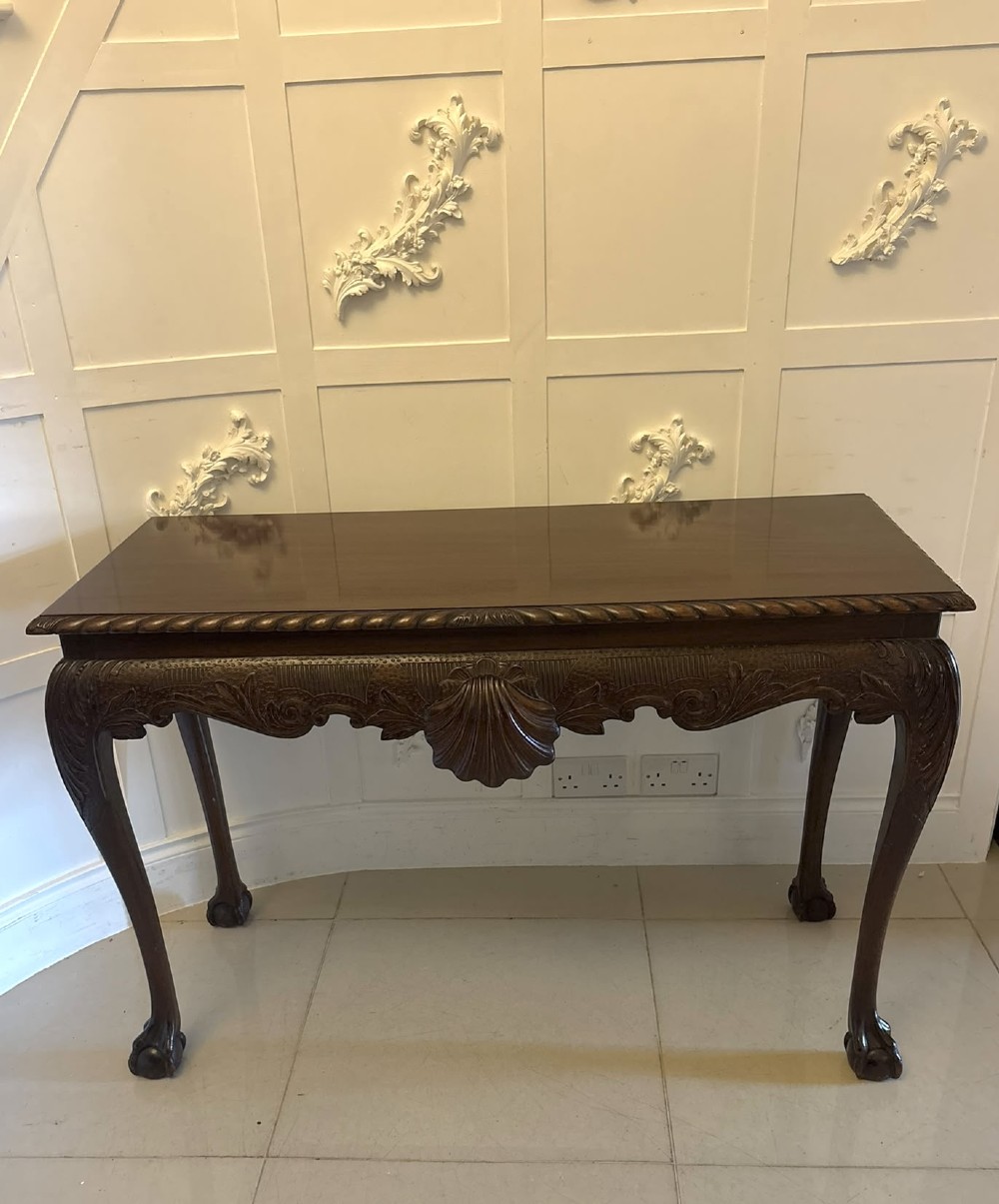 A Victorian carved mahogany console table featuring cabriole legs with ball and claw feet, a shell-carved central apron, and a gadrooned top border.