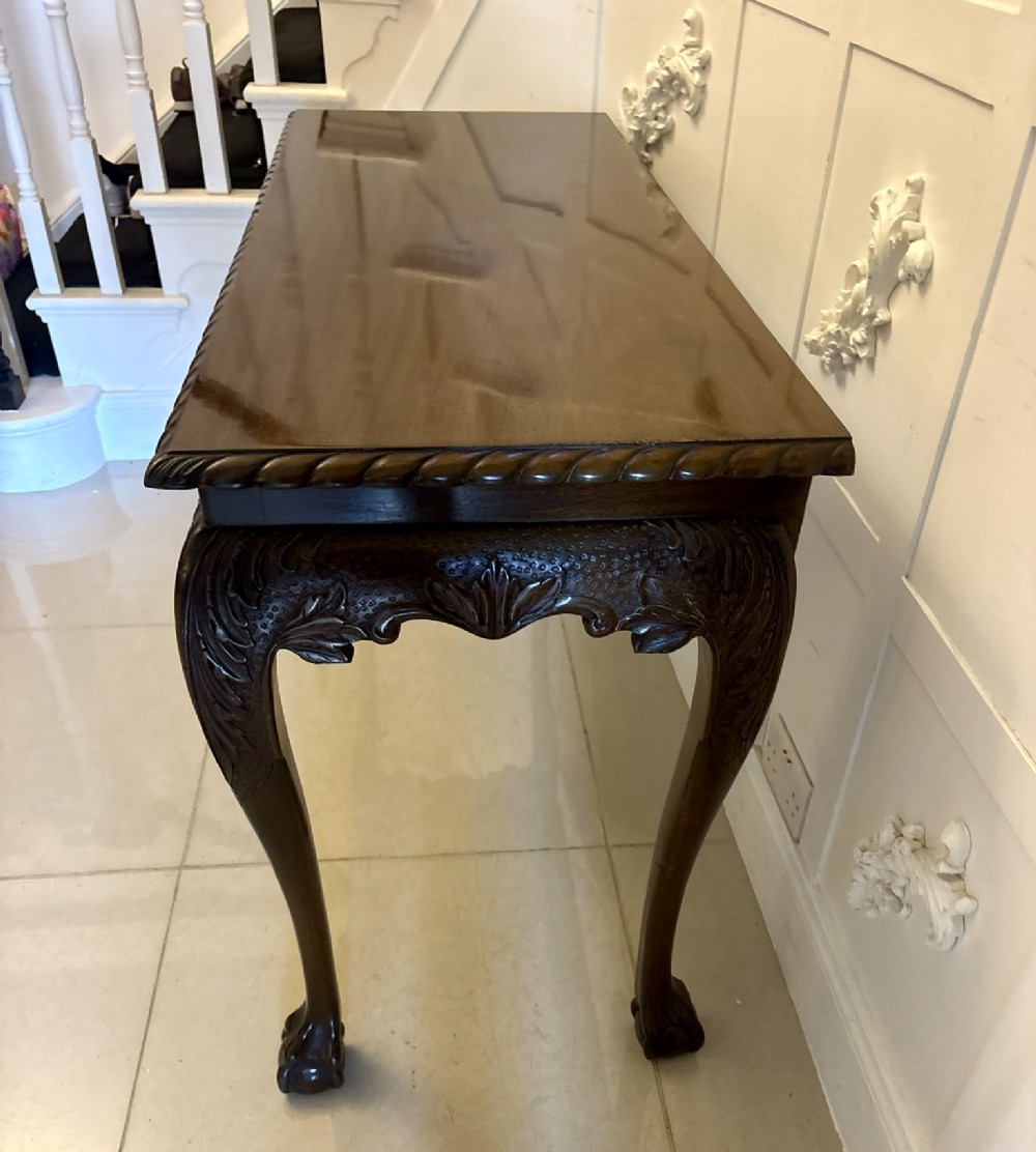 A Victorian carved mahogany console table featuring cabriole legs with ball and claw feet, a shell-carved central apron, and a gadrooned top border. View X