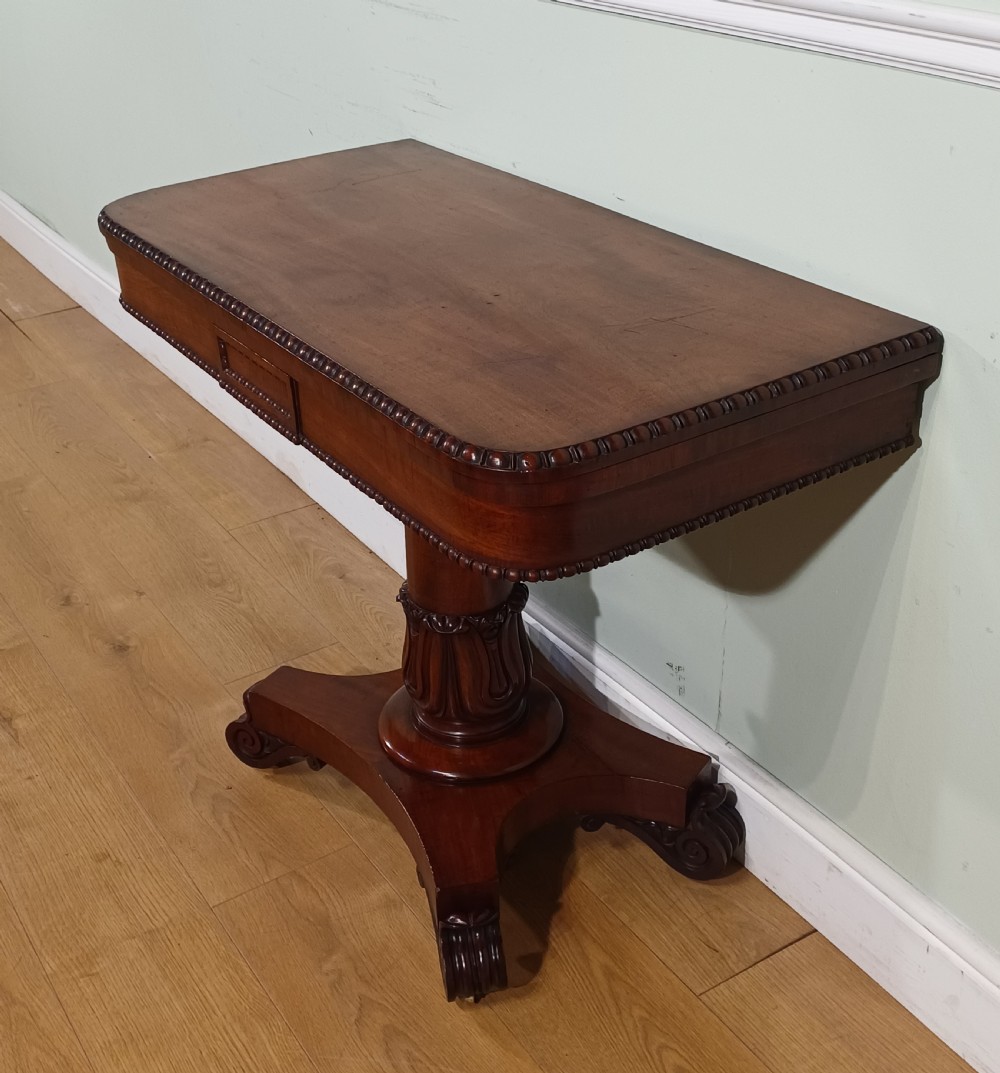 A nineteenth-century mahogany fold-over card table featuring a rectangular top with rounded corners, bead moulding along the frieze, a turned pedestal column, and a quadripartite base with carved scroll feet. View III