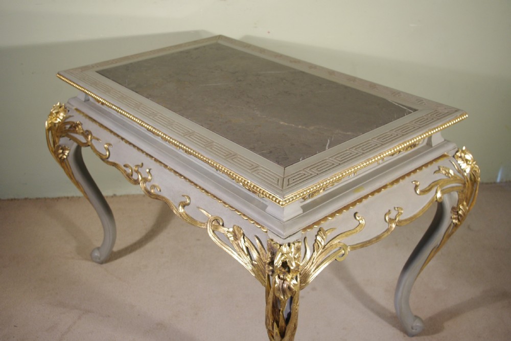 A grey painted rectangular centre table featuring ornate parcel-gilt leaf carvings on cabriole legs and an inset grey marble top. View VI