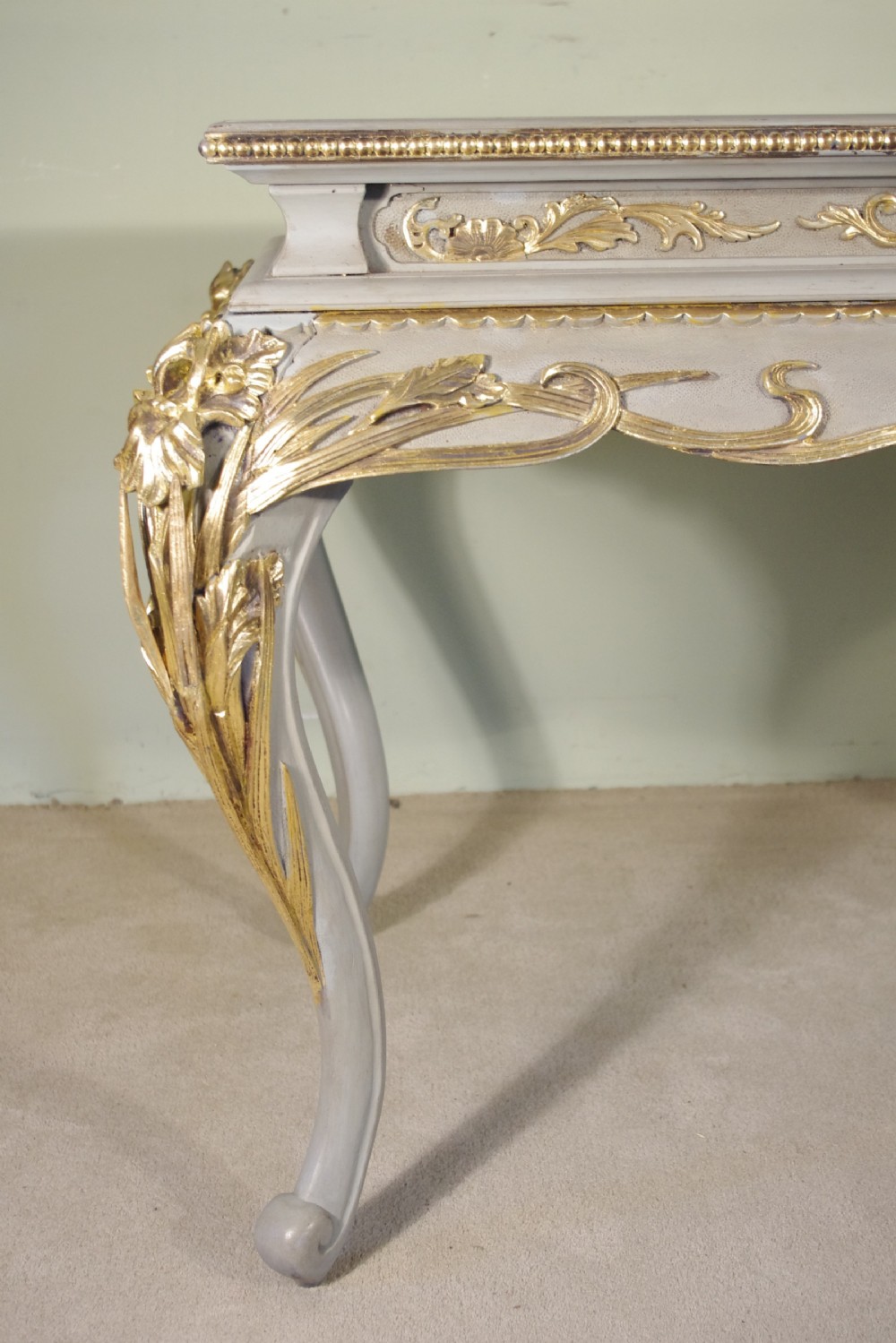 A grey painted rectangular centre table featuring ornate parcel-gilt leaf carvings on cabriole legs and an inset grey marble top. View X