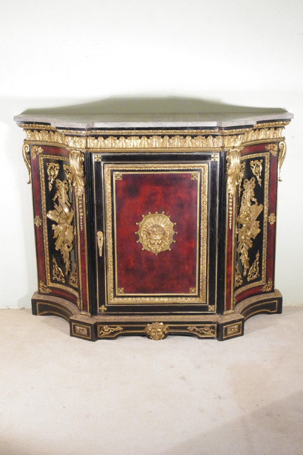 A 19th-century French ebonised side cabinet featuring gilt-metal mounts, a central red panel with a classical medallion, and a contoured marble top.