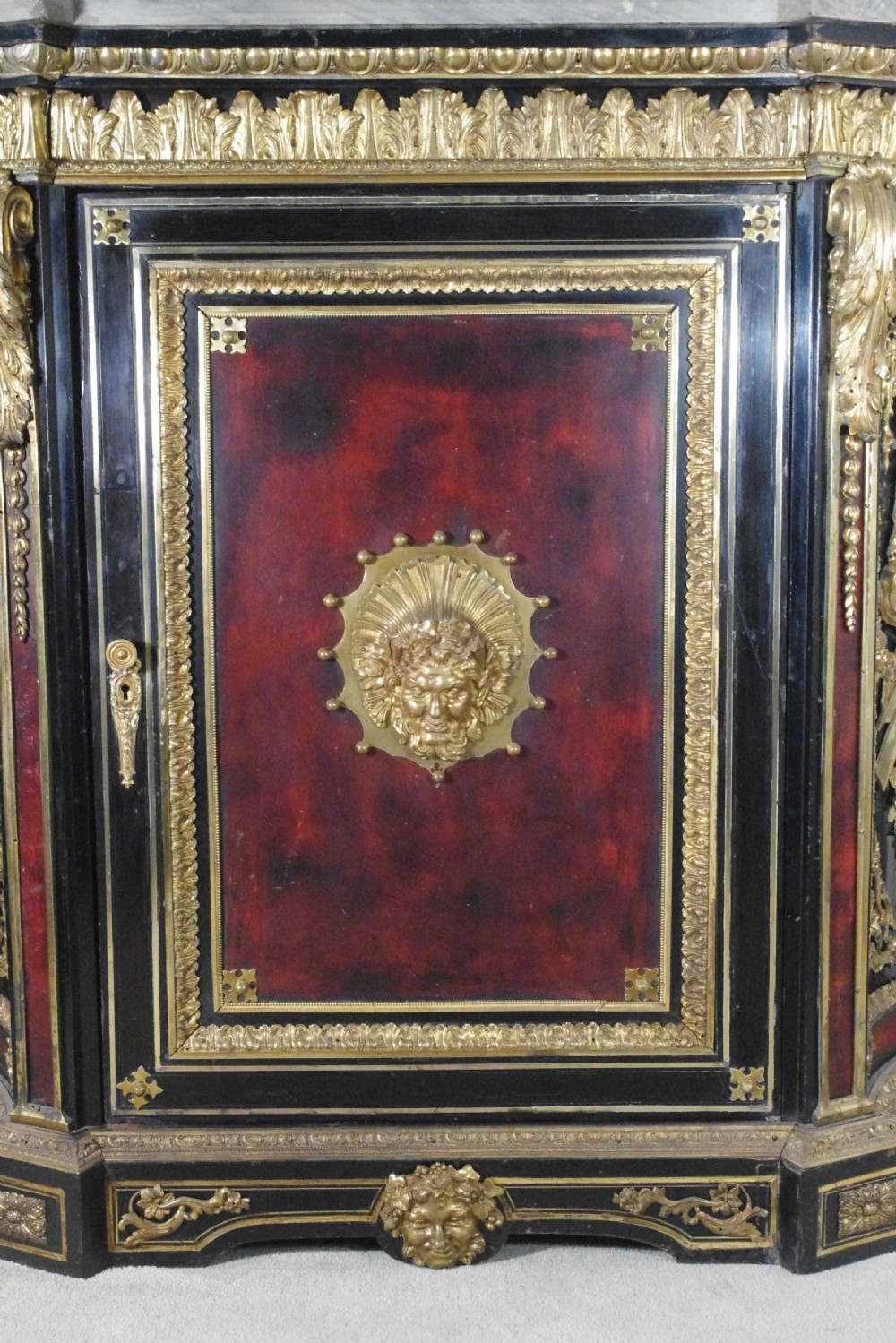 A 19th-century French ebonised side cabinet featuring gilt-metal mounts, a central red panel with a classical medallion, and a contoured marble top. View X