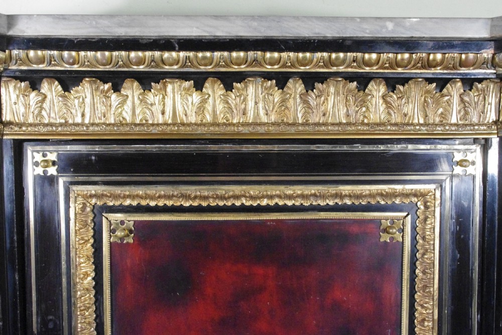 A 19th-century French ebonised side cabinet featuring gilt-metal mounts, a central red panel with a classical medallion, and a contoured marble top. View XVIII