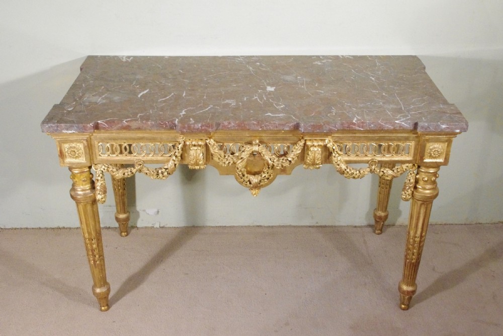 A Louis XVI style giltwood console table with a red veined marble top, carved floral drapes, an openwork frieze, and turned tapered legs. View II