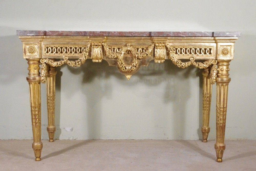 A Louis XVI style giltwood console table with a red veined marble top, carved floral drapes, an openwork frieze, and turned tapered legs. View III
