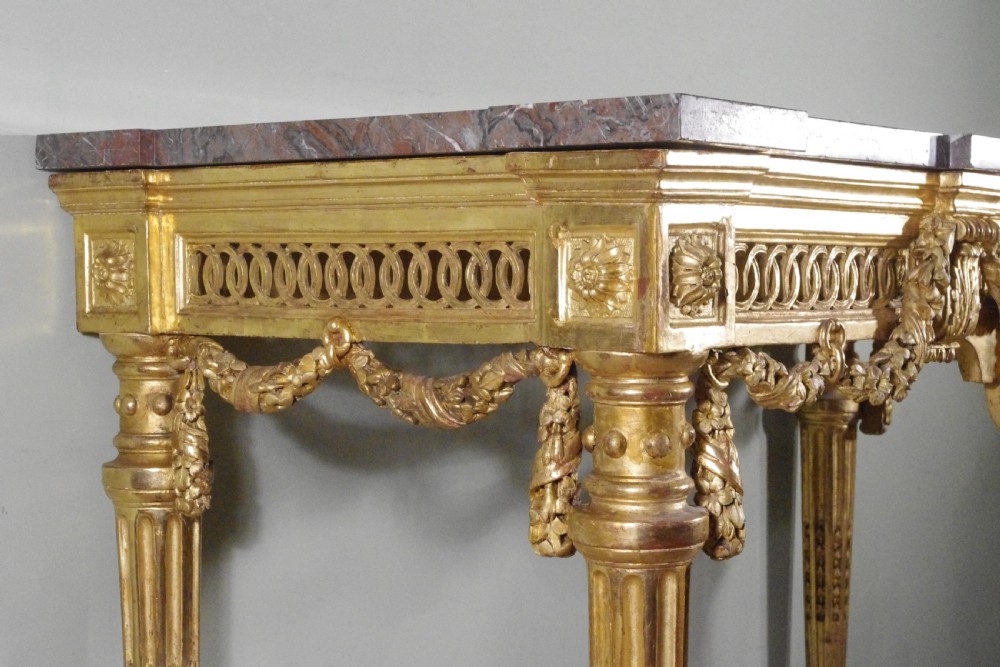 A Louis XVI style giltwood console table with a red veined marble top, carved floral drapes, an openwork frieze, and turned tapered legs. View VIII