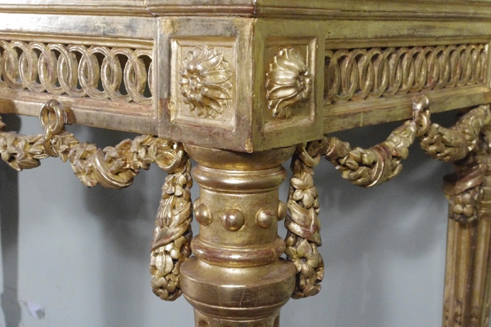A Louis XVI style giltwood console table with a red veined marble top, carved floral drapes, an openwork frieze, and turned tapered legs. View X