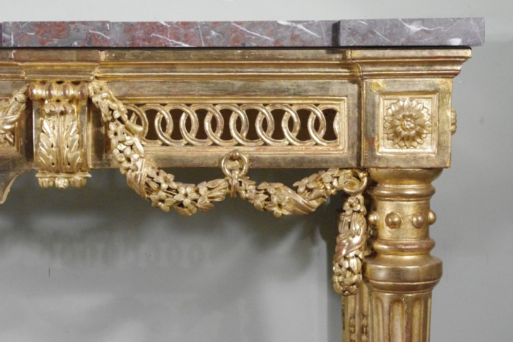A Louis XVI style giltwood console table with a red veined marble top, carved floral drapes, an openwork frieze, and turned tapered legs. View XII