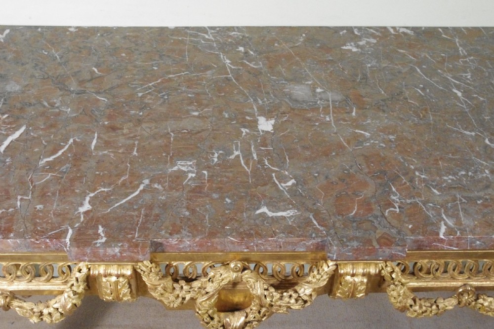A Louis XVI style giltwood console table with a red veined marble top, carved floral drapes, an openwork frieze, and turned tapered legs. View XV