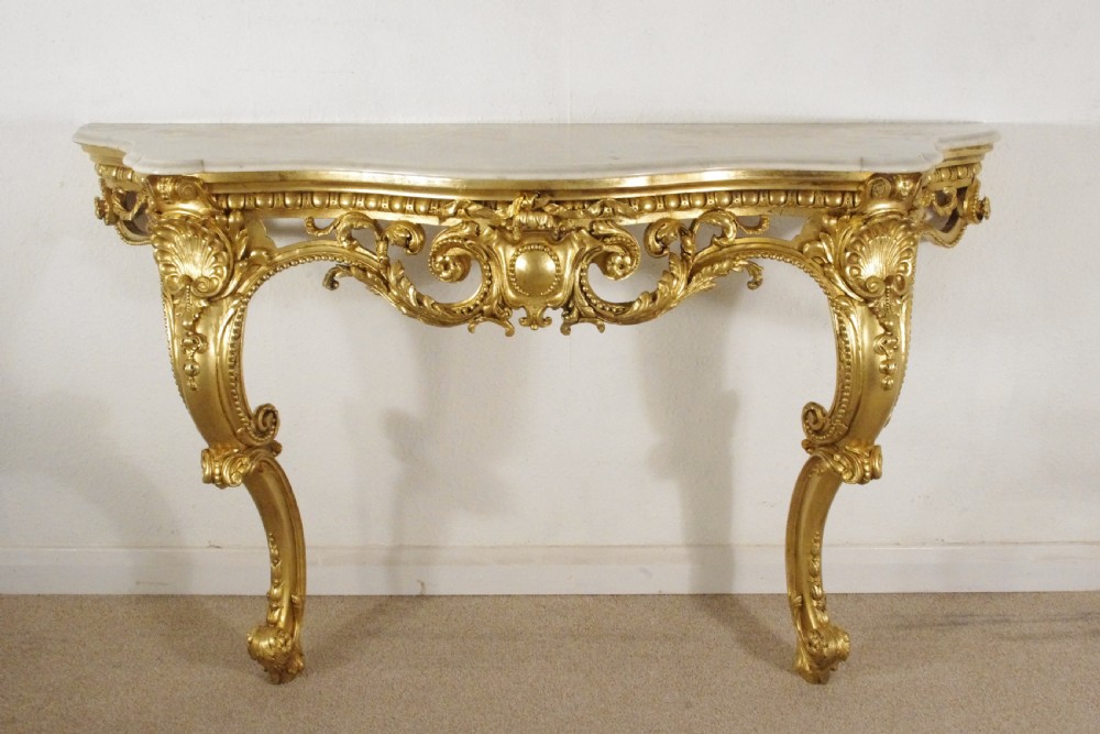 A 19th-century Rococo Revival giltwood console table featuring an ornate carved apron, cabriole legs, and a shaped white marble top. View II