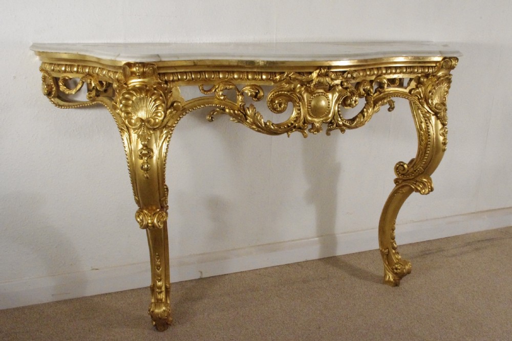 A 19th-century Rococo Revival giltwood console table featuring an ornate carved apron, cabriole legs, and a shaped white marble top. View VI