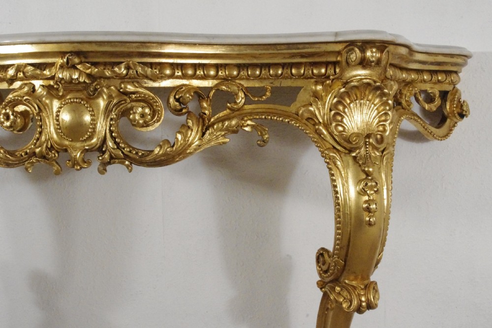 A 19th-century Rococo Revival giltwood console table featuring an ornate carved apron, cabriole legs, and a shaped white marble top. View VII
