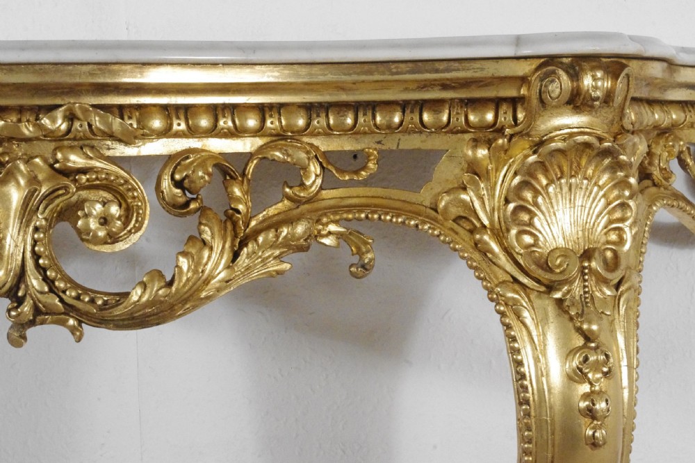 A 19th-century Rococo Revival giltwood console table featuring an ornate carved apron, cabriole legs, and a shaped white marble top. View VIII