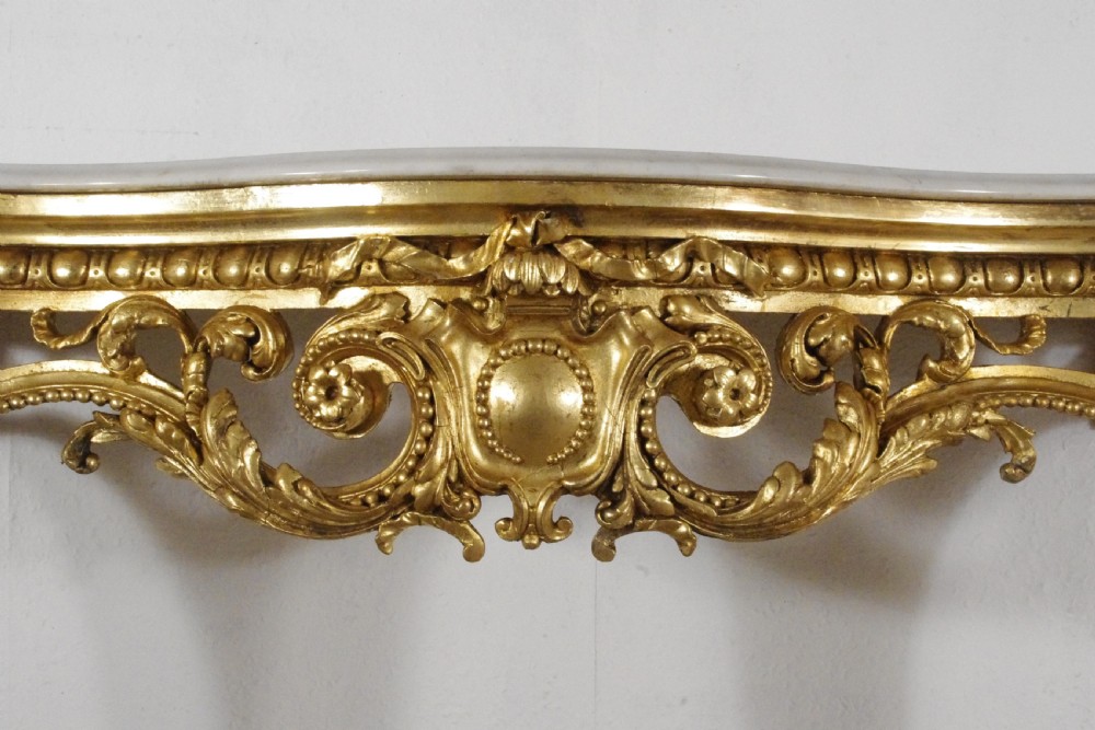 A 19th-century Rococo Revival giltwood console table featuring an ornate carved apron, cabriole legs, and a shaped white marble top. View IX