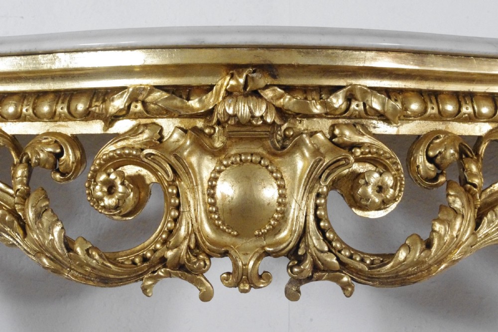 A 19th-century Rococo Revival giltwood console table featuring an ornate carved apron, cabriole legs, and a shaped white marble top. View X