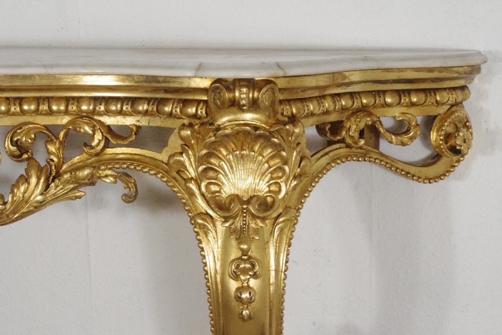 A 19th-century Rococo Revival giltwood console table featuring an ornate carved apron, cabriole legs, and a shaped white marble top. View XI