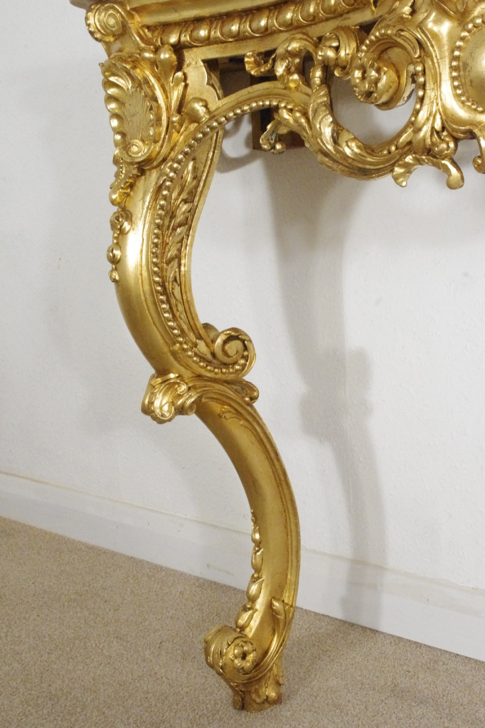 A 19th-century Rococo Revival giltwood console table featuring an ornate carved apron, cabriole legs, and a shaped white marble top. View XII