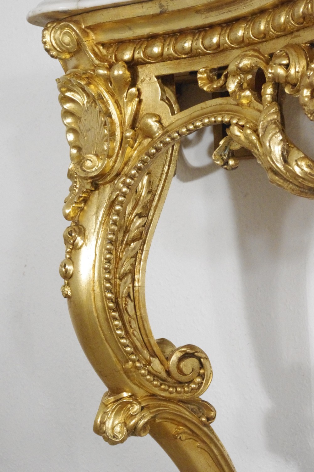 A 19th-century Rococo Revival giltwood console table featuring an ornate carved apron, cabriole legs, and a shaped white marble top. View XIII
