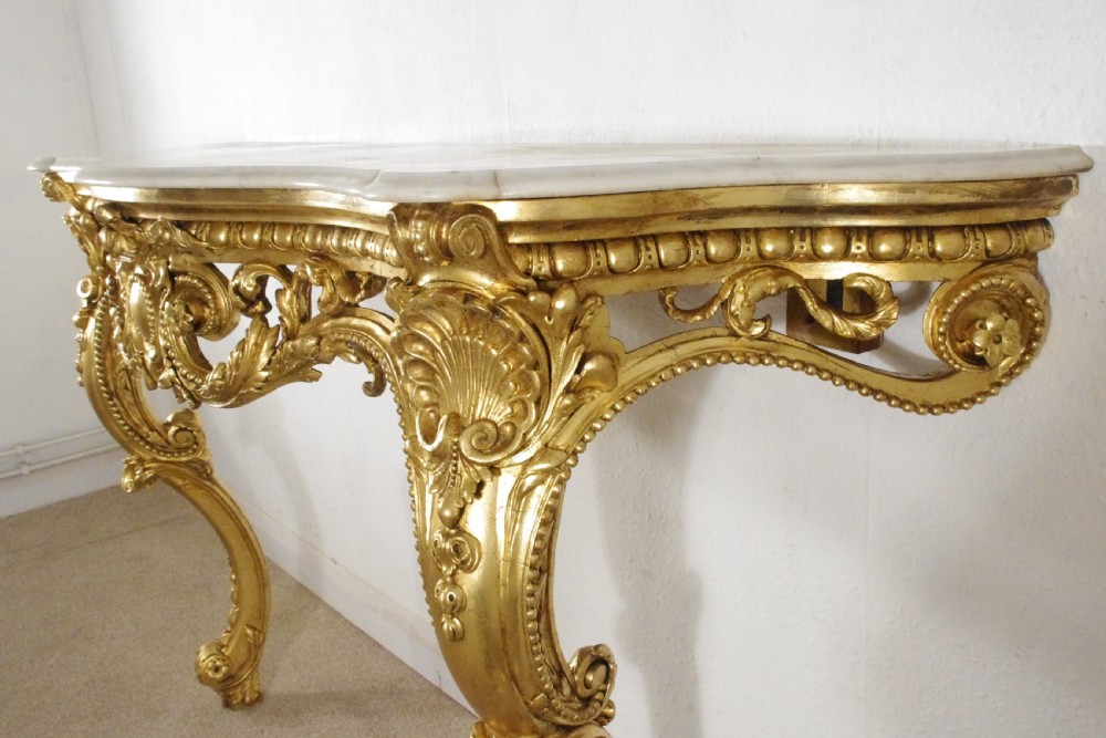 A 19th-century Rococo Revival giltwood console table featuring an ornate carved apron, cabriole legs, and a shaped white marble top. View XV