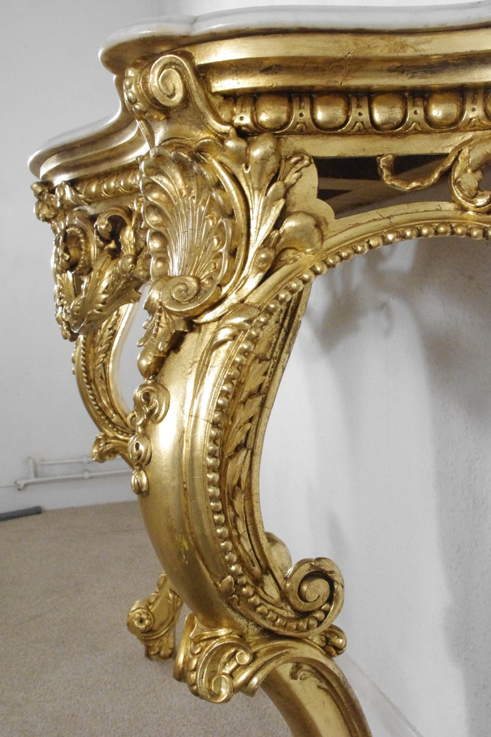 A 19th-century Rococo Revival giltwood console table featuring an ornate carved apron, cabriole legs, and a shaped white marble top. View XVI
