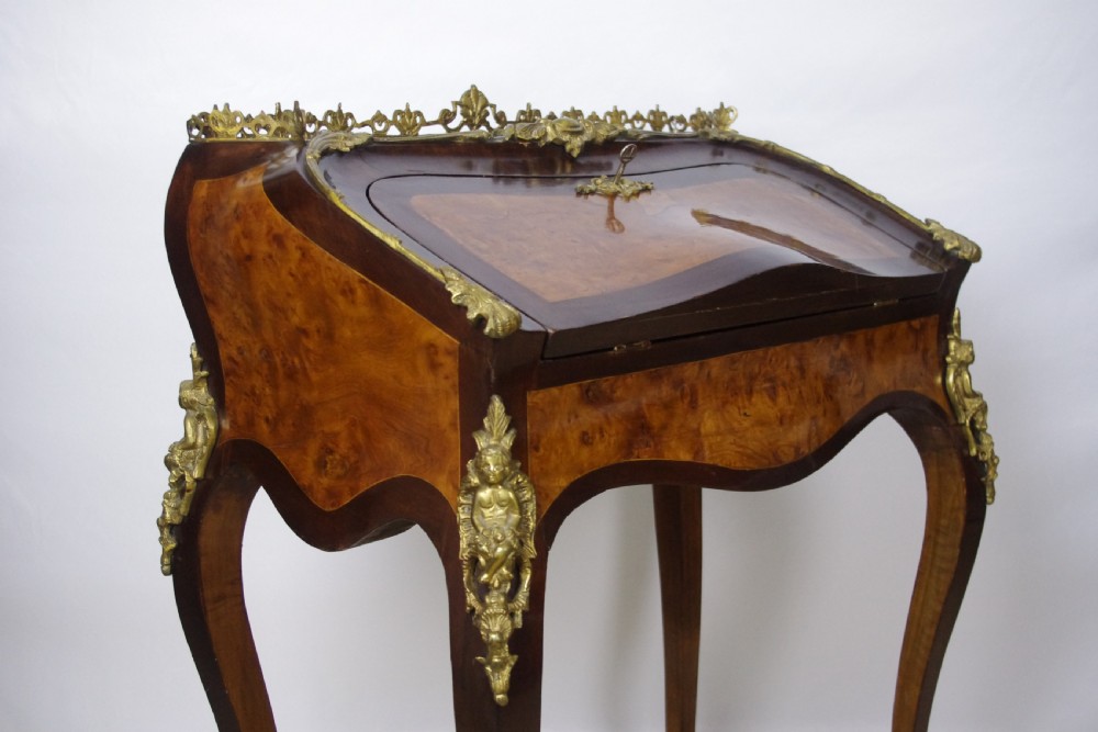 A French Louis XV style bureau de dame constructed from burr walnut veneer with cabriole legs and ornate gilt metal mounts. View V