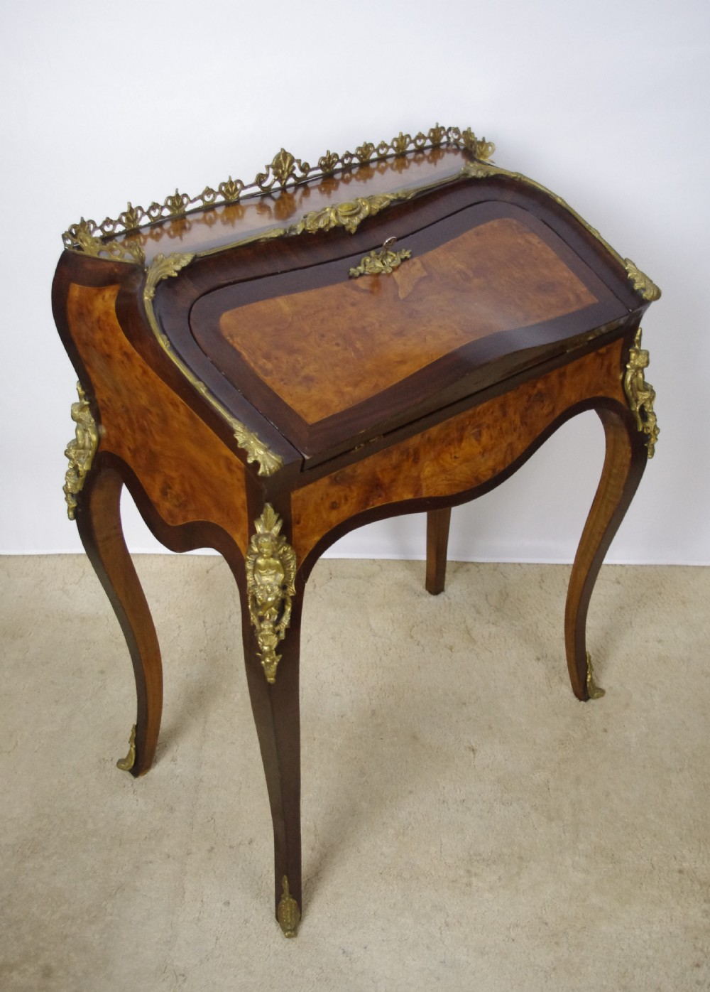 A French Louis XV style bureau de dame constructed from burr walnut veneer with cabriole legs and ornate gilt metal mounts. View X