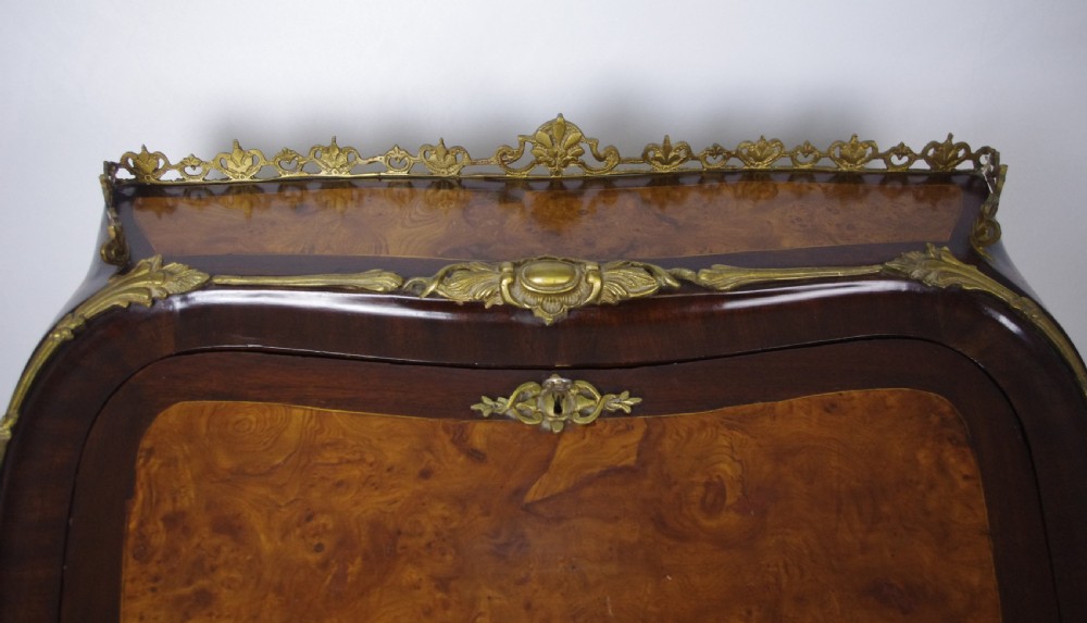 A French Louis XV style bureau de dame constructed from burr walnut veneer with cabriole legs and ornate gilt metal mounts. View XV