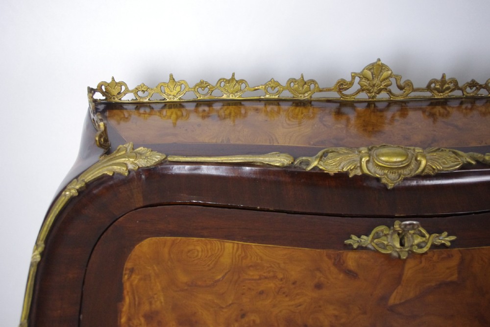 A French Louis XV style bureau de dame constructed from burr walnut veneer with cabriole legs and ornate gilt metal mounts. View XVI