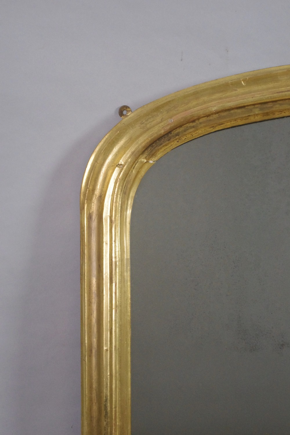 A Victorian giltwood overmantel mirror featuring a gently arched top frame and carved acanthus scroll corner details. View II