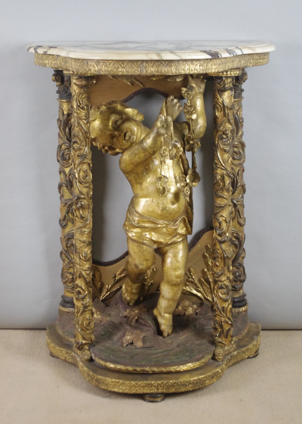 A 19th-century giltwood console table featuring a central carved putto figure with floral accents beneath a shaped marble top.