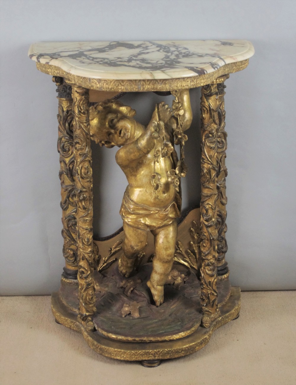 A 19th-century giltwood console table featuring a central carved putto figure with floral accents beneath a shaped marble top. View II