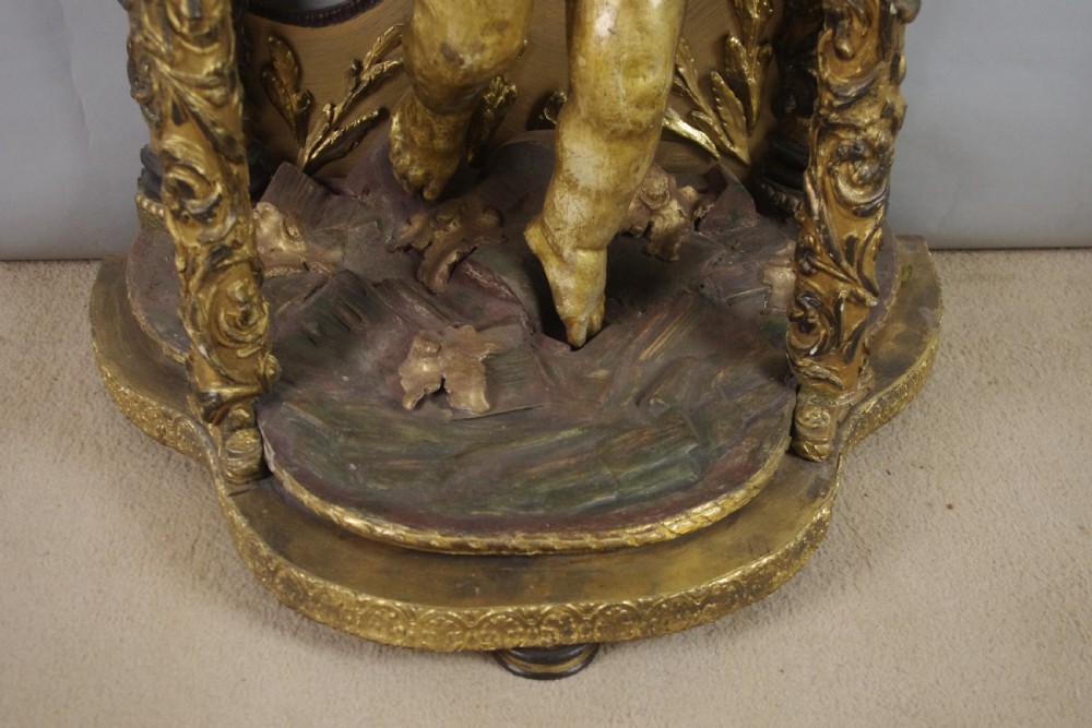 A 19th-century giltwood console table featuring a central carved putto figure with floral accents beneath a shaped marble top. View X