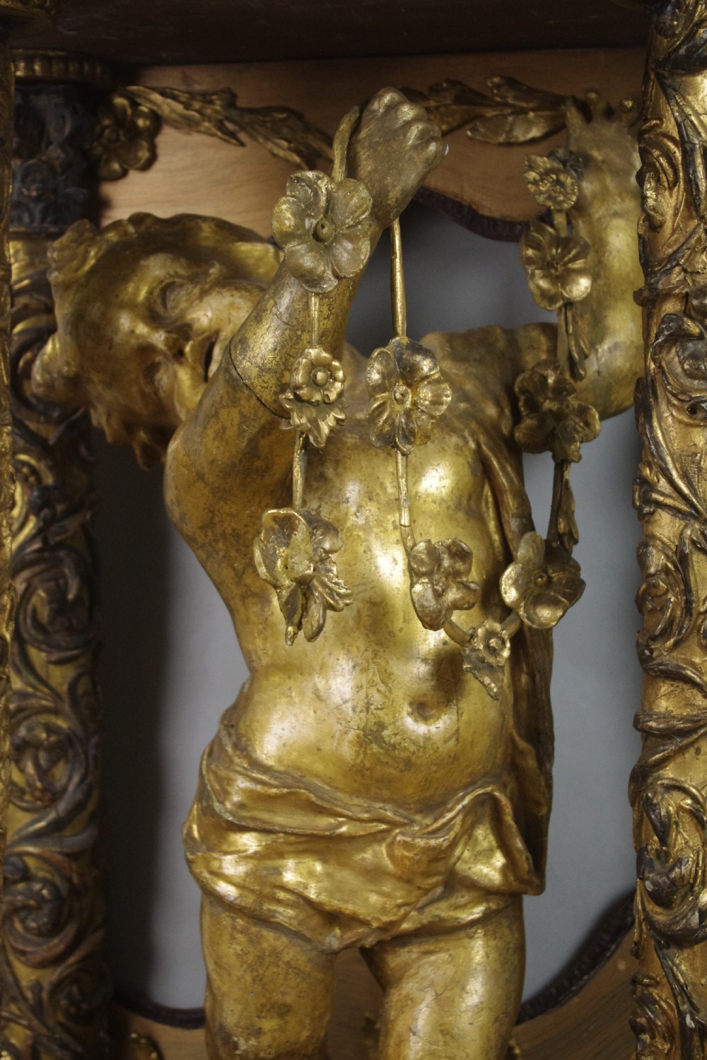 A 19th-century giltwood console table featuring a central carved putto figure with floral accents beneath a shaped marble top. View XII