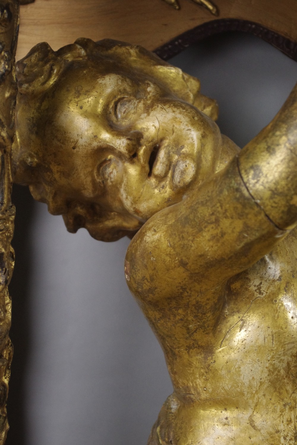 A 19th-century giltwood console table featuring a central carved putto figure with floral accents beneath a shaped marble top. View XIII