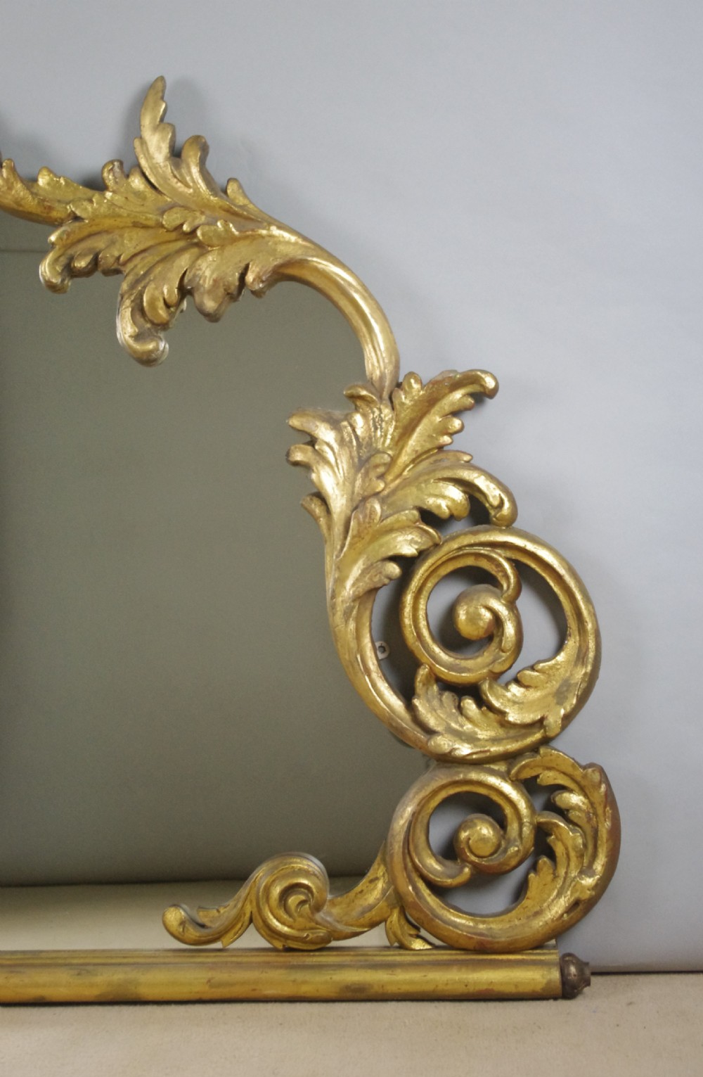 An ornate French giltwood overmantel mirror featuring carved acanthus leaf cresting along an arched frame with a straight base rail. View III