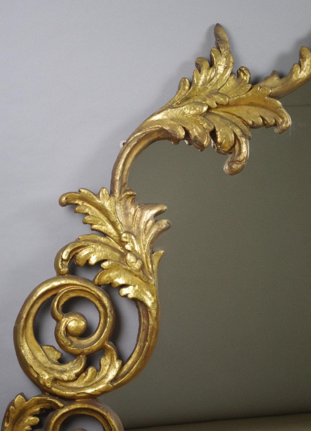An ornate French giltwood overmantel mirror featuring carved acanthus leaf cresting along an arched frame with a straight base rail. View V