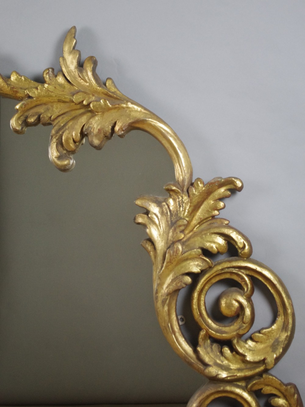 An ornate French giltwood overmantel mirror featuring carved acanthus leaf cresting along an arched frame with a straight base rail. View VI