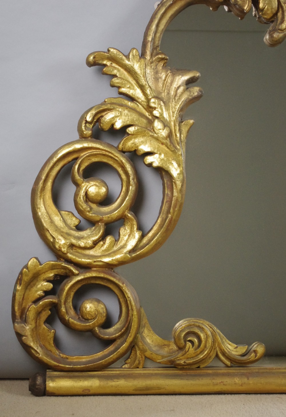 An ornate French giltwood overmantel mirror featuring carved acanthus leaf cresting along an arched frame with a straight base rail. View VII