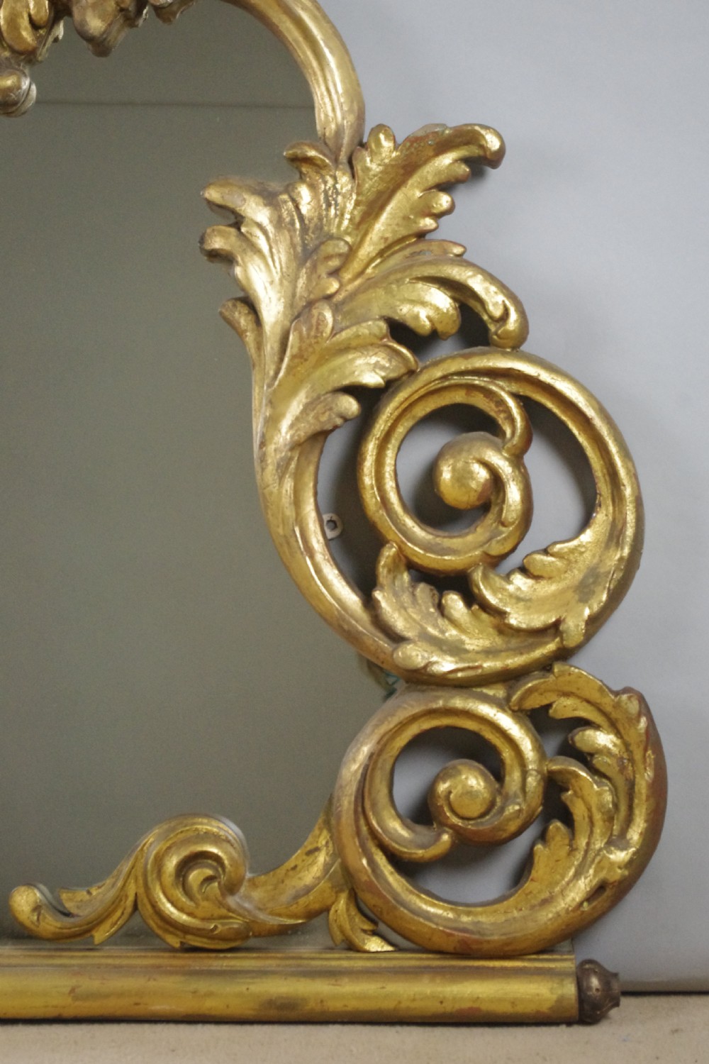 An ornate French giltwood overmantel mirror featuring carved acanthus leaf cresting along an arched frame with a straight base rail. View VIII