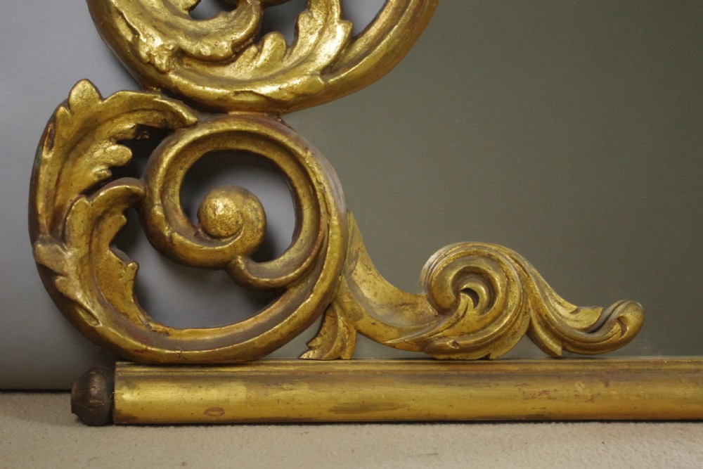 An ornate French giltwood overmantel mirror featuring carved acanthus leaf cresting along an arched frame with a straight base rail. View IX