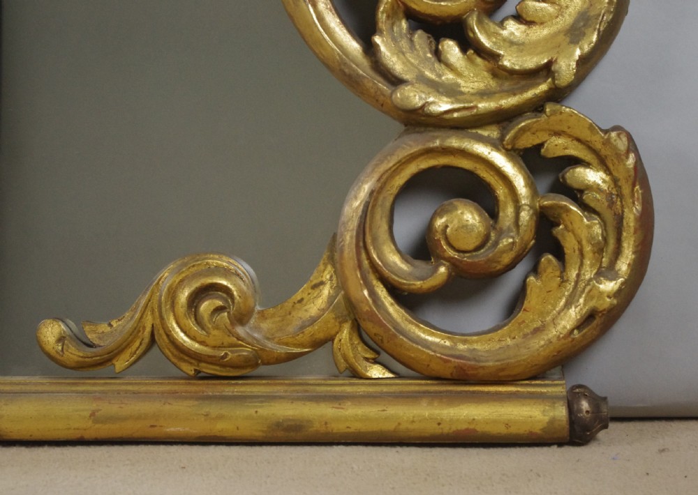 An ornate French giltwood overmantel mirror featuring carved acanthus leaf cresting along an arched frame with a straight base rail. View X