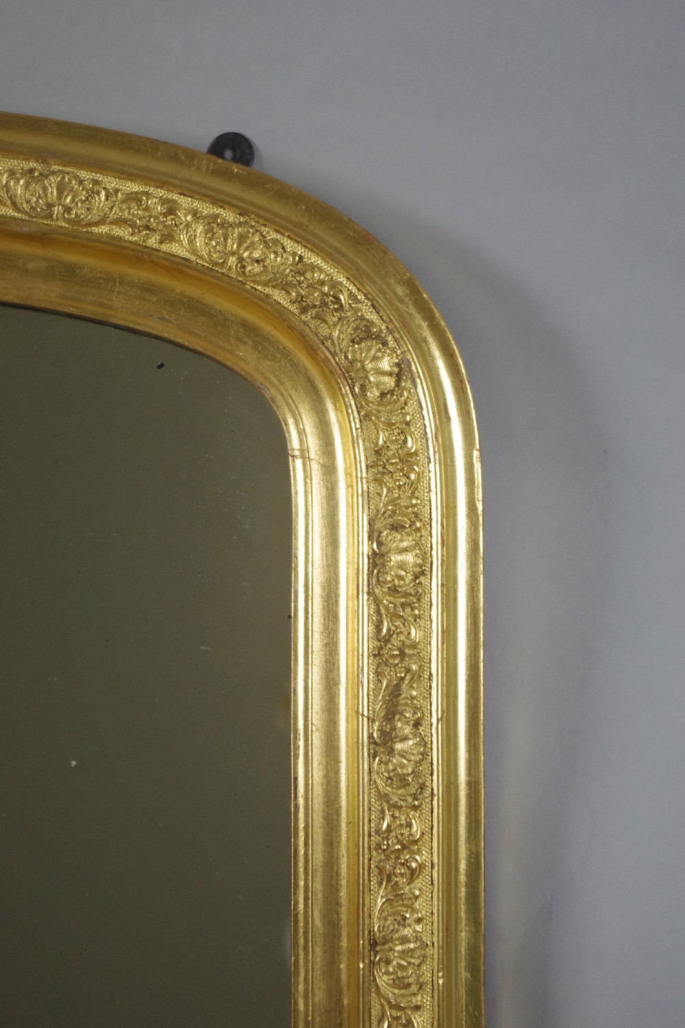 A large Victorian gold gilded overmantel mirror featuring an arched upper frame decorated with relief moulded floral scrollwork. View V