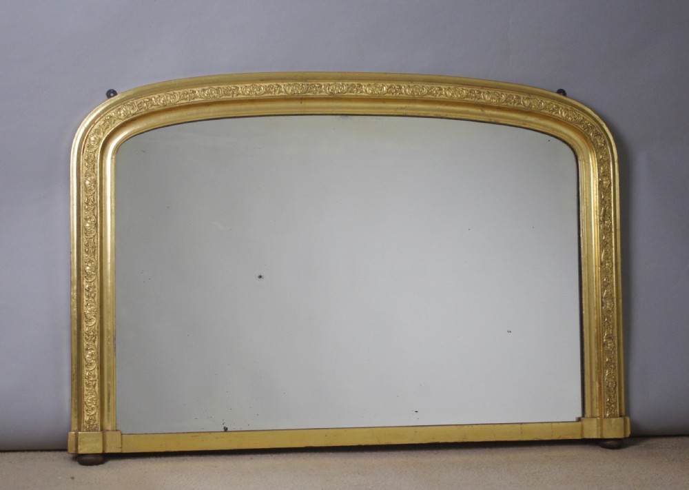 A large Victorian gold gilded overmantel mirror featuring an arched upper frame decorated with relief moulded floral scrollwork. View VIII
