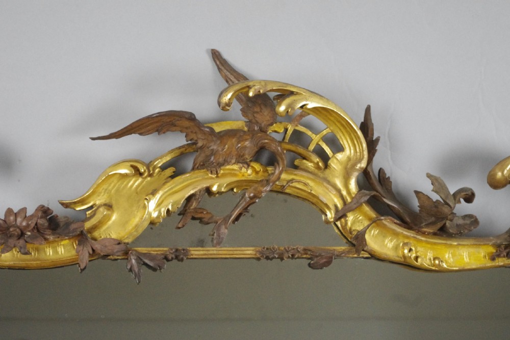 Large Victorian Rococo style giltwood overmantel mirror featuring elaborate carved foliate trails, asymmetric C-scrolls, and a scrolling top crest. View V